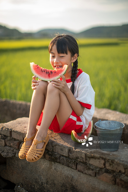 夏天的稻田里吃西瓜的小女孩图片素材