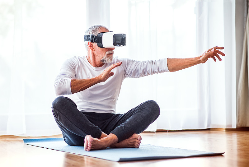 老人戴著VR眼鏡在家鍛煉。圖片素材