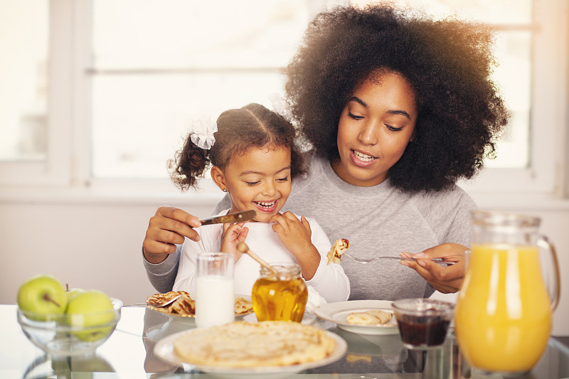 非裔美國人年輕的母親和女兒正在吃早餐圖片素材