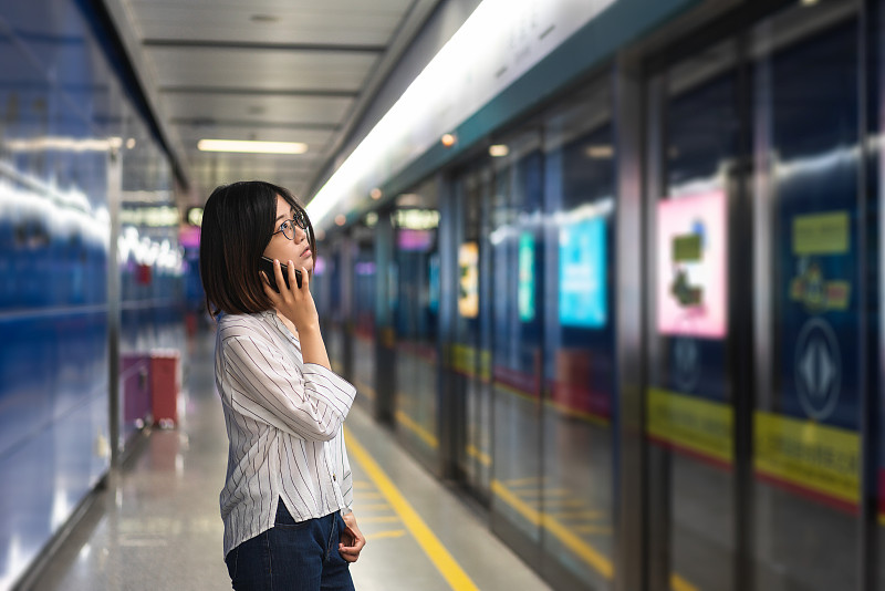 一個亞洲女人在地鐵站里打電話圖片素材