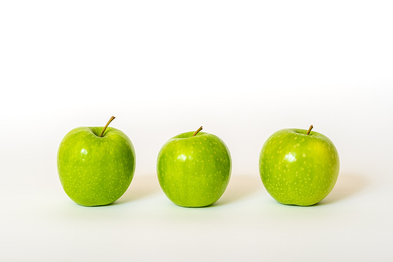 三个新鲜的青苹果排成一列图片