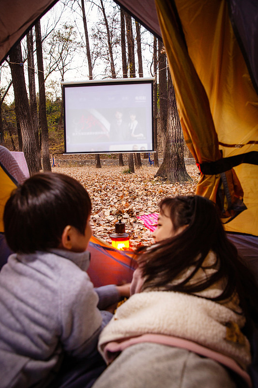戶外露營的兒童趴在帳篷里看電影圖片素材