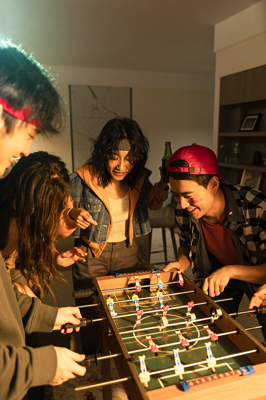 快樂的年輕人在客廳玩桌上足球圖片素材