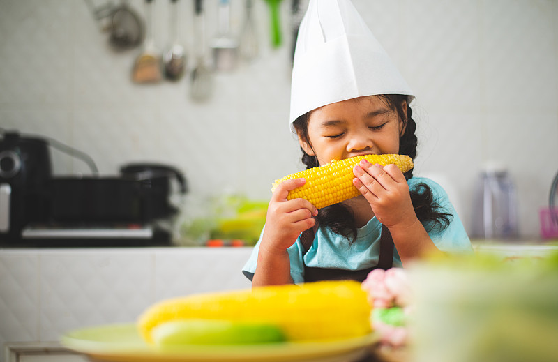 在廚房訓練烹飪后，孩子們在休息時間吃玉米圖片素材