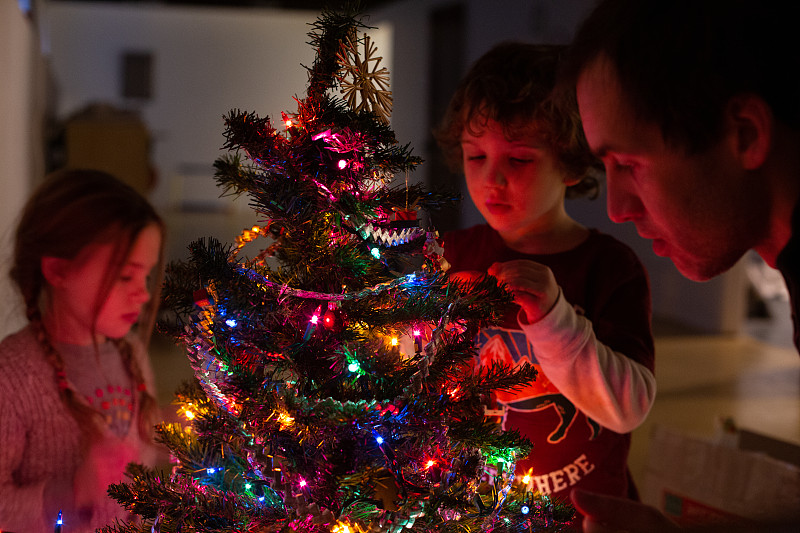 一個年輕的家庭在晚上裝飾他們的圣誕樹圖片素材
