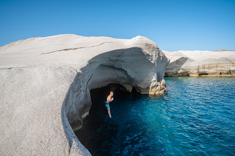 希臘米洛斯的薩拉基尼科，一名男子從白色懸崖上跳水攝影圖片
