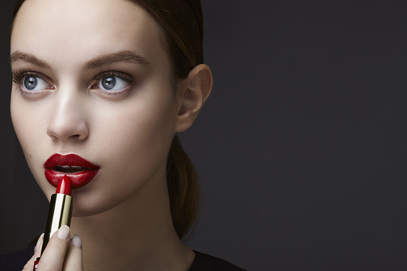 年輕女子涂抹口紅的化妝品肖像圖片素材