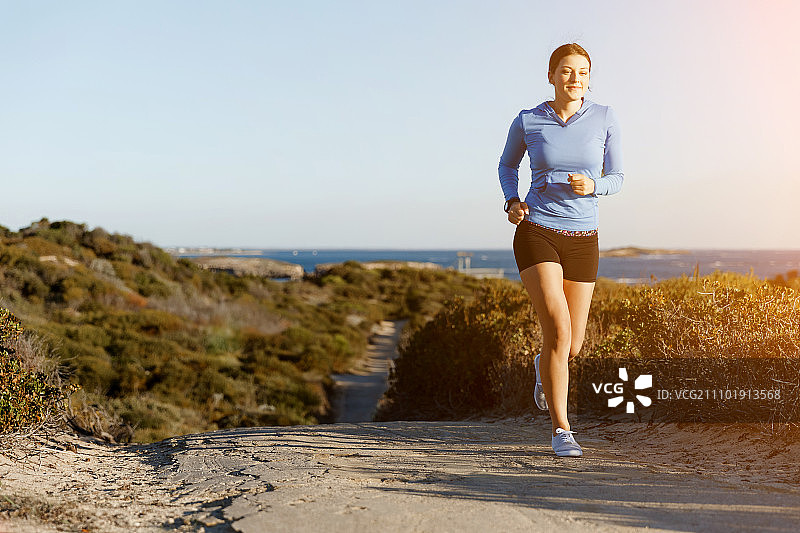 运动跑步者在海滩慢跑锻炼。适合女性健身模型沿海洋慢跑图片素材