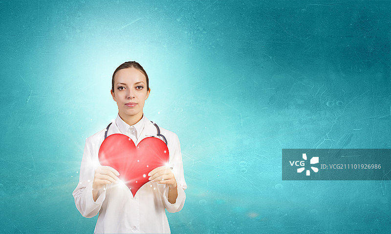 专业呵护你的心脏。有吸引力的保健女工作者与红心的象征图片素材