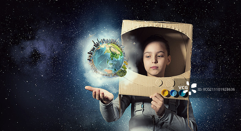 我将探索太空。头上戴着纸箱头盔的可爱女孩梦想着成为宇航员。这张照片的元素是由美国宇航局提供的图片素材