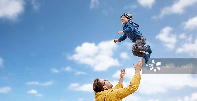 家庭，童年，父亲，休闲和人的概念-快乐的父亲和儿子在户外玩，在蓝天和云彩的背景下图片素材