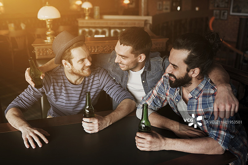 人，休闲，友谊和单身派对的概念-快乐的男性朋友喝瓶装啤酒和拥抱在酒吧或酒吧图片素材