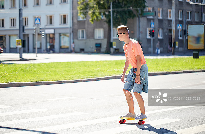 暑假，极限运动和人的概念-十几岁的男孩骑短现代巡洋船滑板在人行横道上的城市图片素材