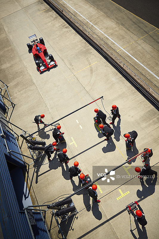 维修站工作人员准备接近一级方程式赛车在维修站车道图片素材