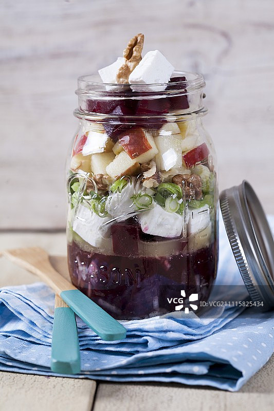 甜菜根，山羊奶酪，苹果，核桃，橄榄和洋葱放在一个玻璃罐里图片素材