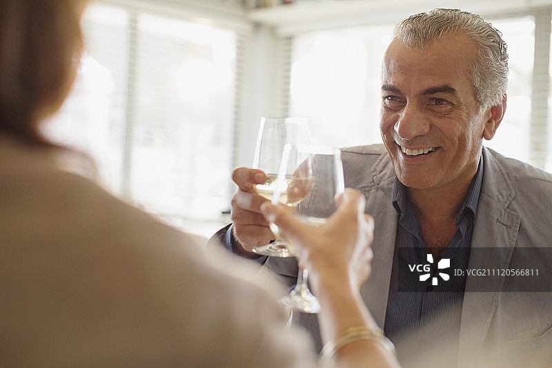 微笑的老男人喝酒，与女人在餐厅敬酒图片素材
