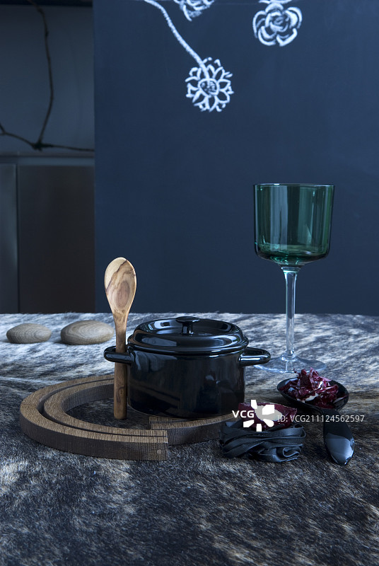 特写的小黑锅与木勺和葡萄酒杯盖上的桌子图片素材