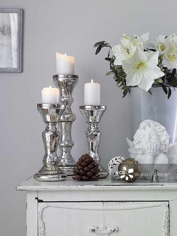 鲍尔银色烛台与白色盖子蜡烛和花在桌子上图片素材