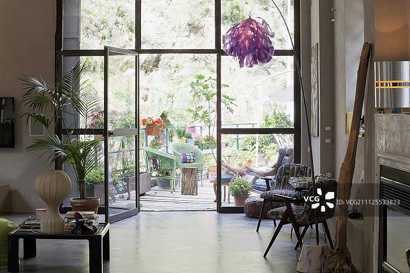 阁楼公寓里的家具和物品的艺术收藏，在玻璃墙前，阳台上可以看到绿色植物图片素材