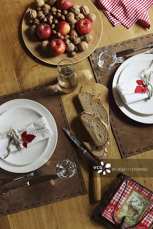 装饰缝制的皮革餐垫的节日餐位设置;一盘苹果和坚果图片素材