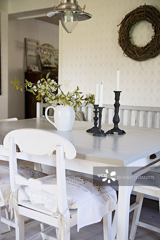 白色厨房椅与弯曲靠背的餐桌和柳条花环墙上在乡村室内图片素材
