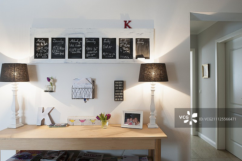 现代木桌，两盏台灯，下框的黑板在墙上图片素材