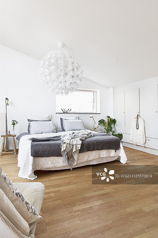阁楼卧室有双人床，木地板和白色，球形灯罩与花形部分图片素材