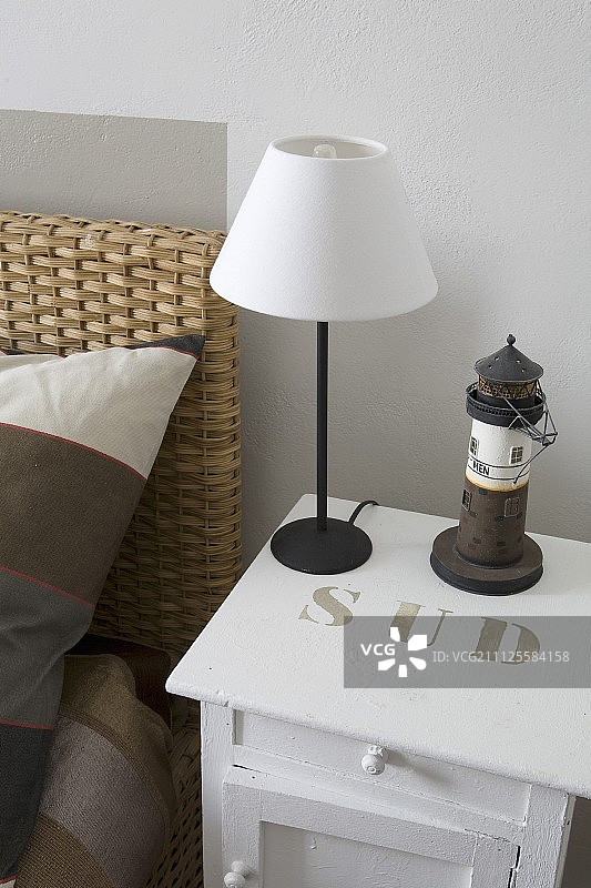 极简主义的台灯，白色灯罩，白色油漆的床头柜上有模板刻字图片素材