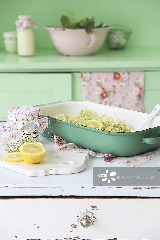 接骨木花和柠檬放在绿色的烤箱盘里，放在白色的复古橱柜里图片素材