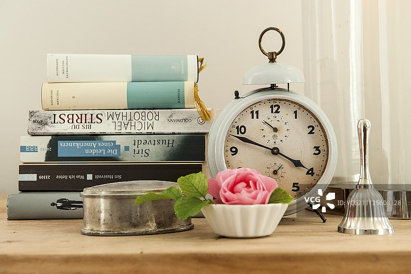 银锡和玫瑰在锅前堆积的书籍和复古风格的闹钟图片素材