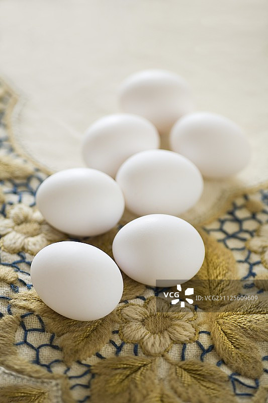 白色的鸡蛋放在花绣花的复古桌布上图片素材