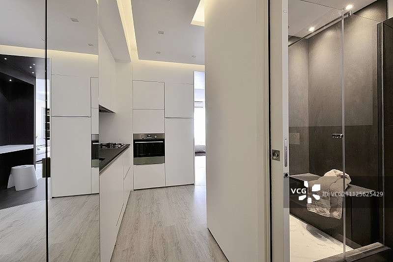 开放式的大厅区域在设计师公寓，配备白色厨房柜台，滑动门和可以看到浴室图片素材