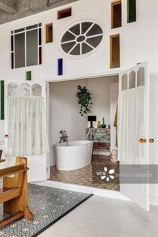 墙与艺术的彩色玻璃元素和白色的观点。浴室的独立式浴缸图片素材