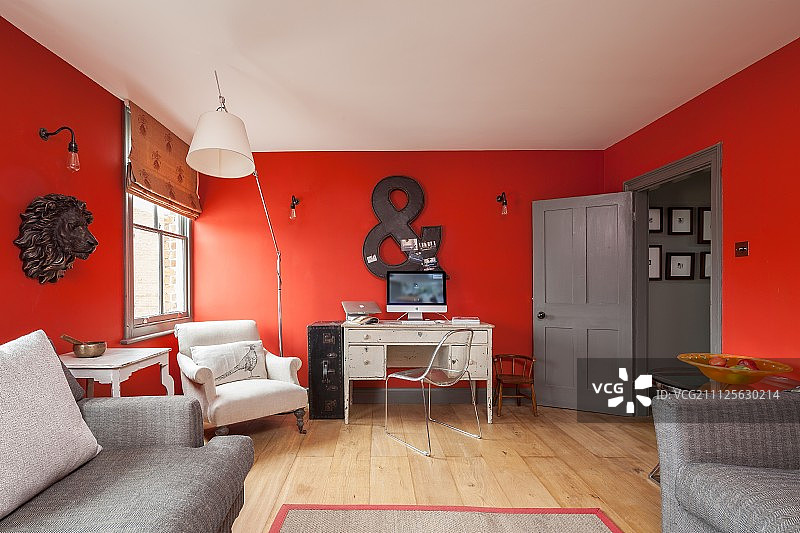 书桌和扶手椅靠红墙在翻新的公寓图片素材