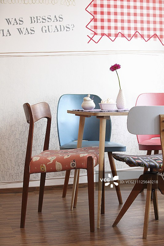 各种复古椅子围绕着非洲菊，蛋白霜和糖碗在桌子上图片素材