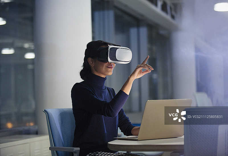 女商人在办公室的笔记本电脑上使用虚拟现实模拟器图片素材