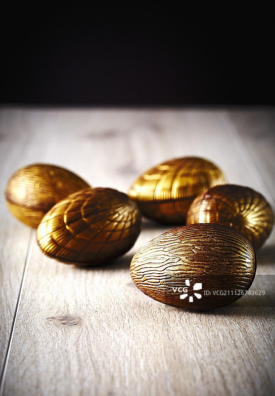 木质表面上的金色巧克力复活节彩蛋图片素材