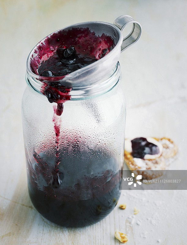 黑莓酱放在漏斗上，放在罐子上图片素材