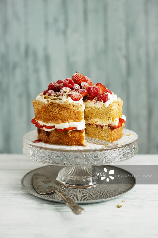 蛋糕架上有奶油、草莓、覆盆子和开心果的维多利亚海绵蛋糕图片素材