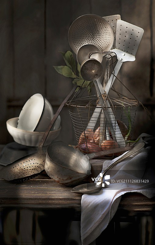 旧厨具放在铁丝篮子里，旁边的木桌上图片素材