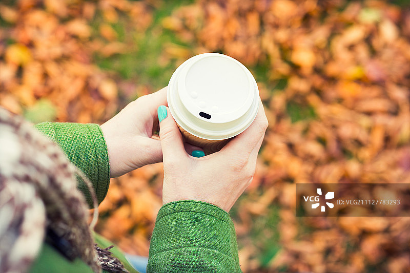 秋天的概念，匿名女子享受外卖咖啡杯在阳光明媚的寒冷秋天的一天图片素材