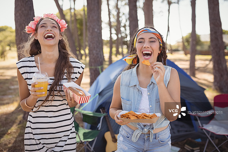 快乐的朋友们在阳光明媚的日子里在森林里露营时吃零食图片素材