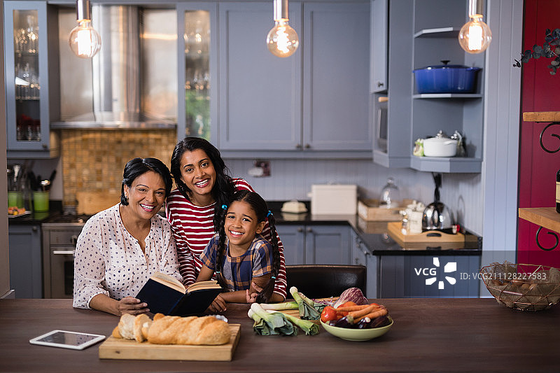 多代同堂的一家人坐在厨房里微笑的肖像图片素材