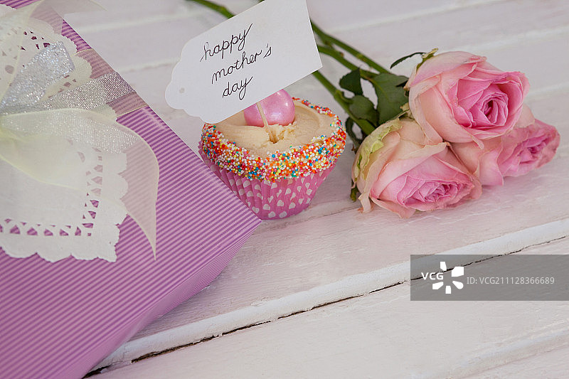 母亲节贺卡，纸杯蛋糕，礼盒和玫瑰花放在桌上图片素材