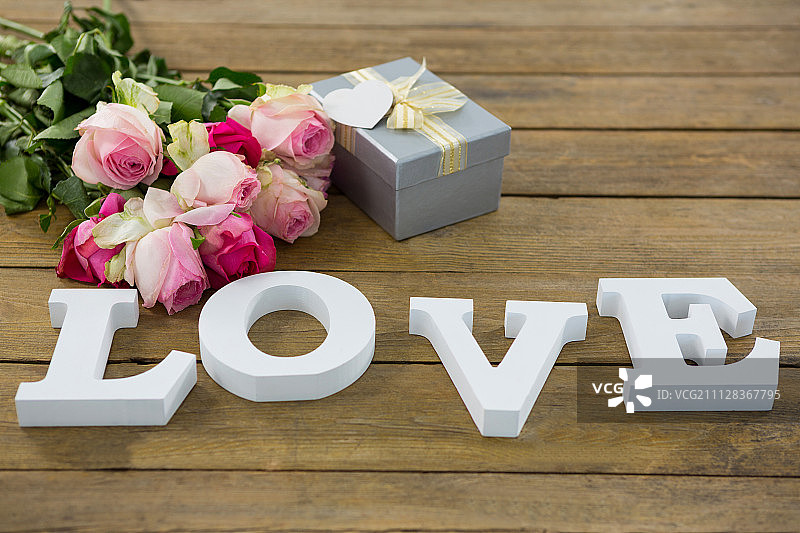 特写礼盒与一束玫瑰和爱字母木板上图片素材