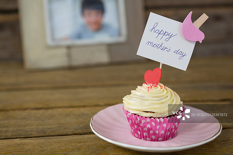 特写美味的纸杯蛋糕与快乐的母亲节标签在木板上图片素材