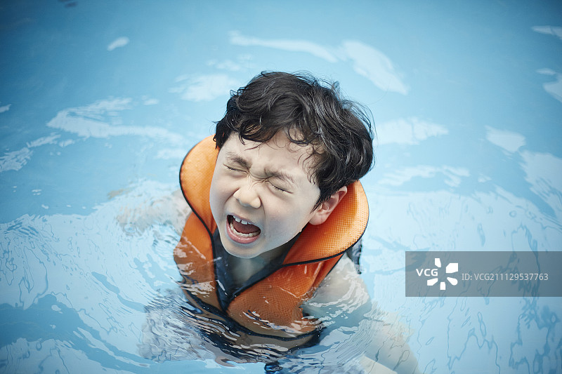 穿着救生衣的男孩在游泳池里哭图片素材
