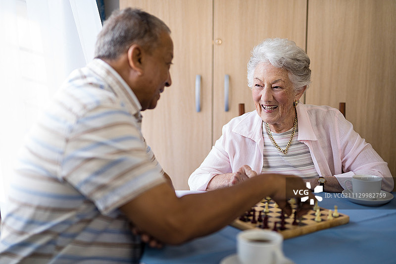 敬老院微笑着下棋的男女老人图片素材
