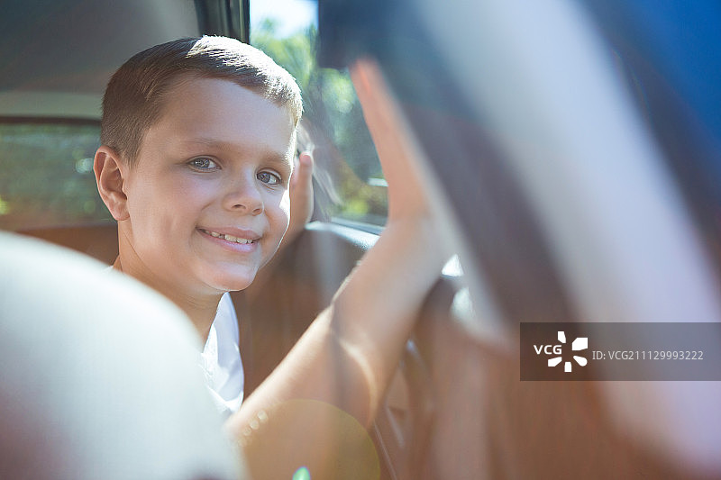 一个快乐的少年坐在汽车后座上的肖像图片素材