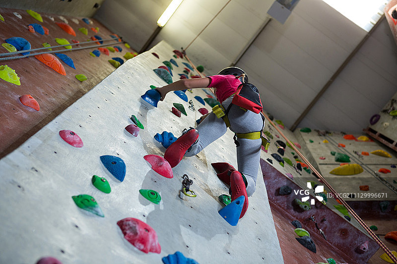 低视角的青少年女孩练习攀岩在健身室图片素材